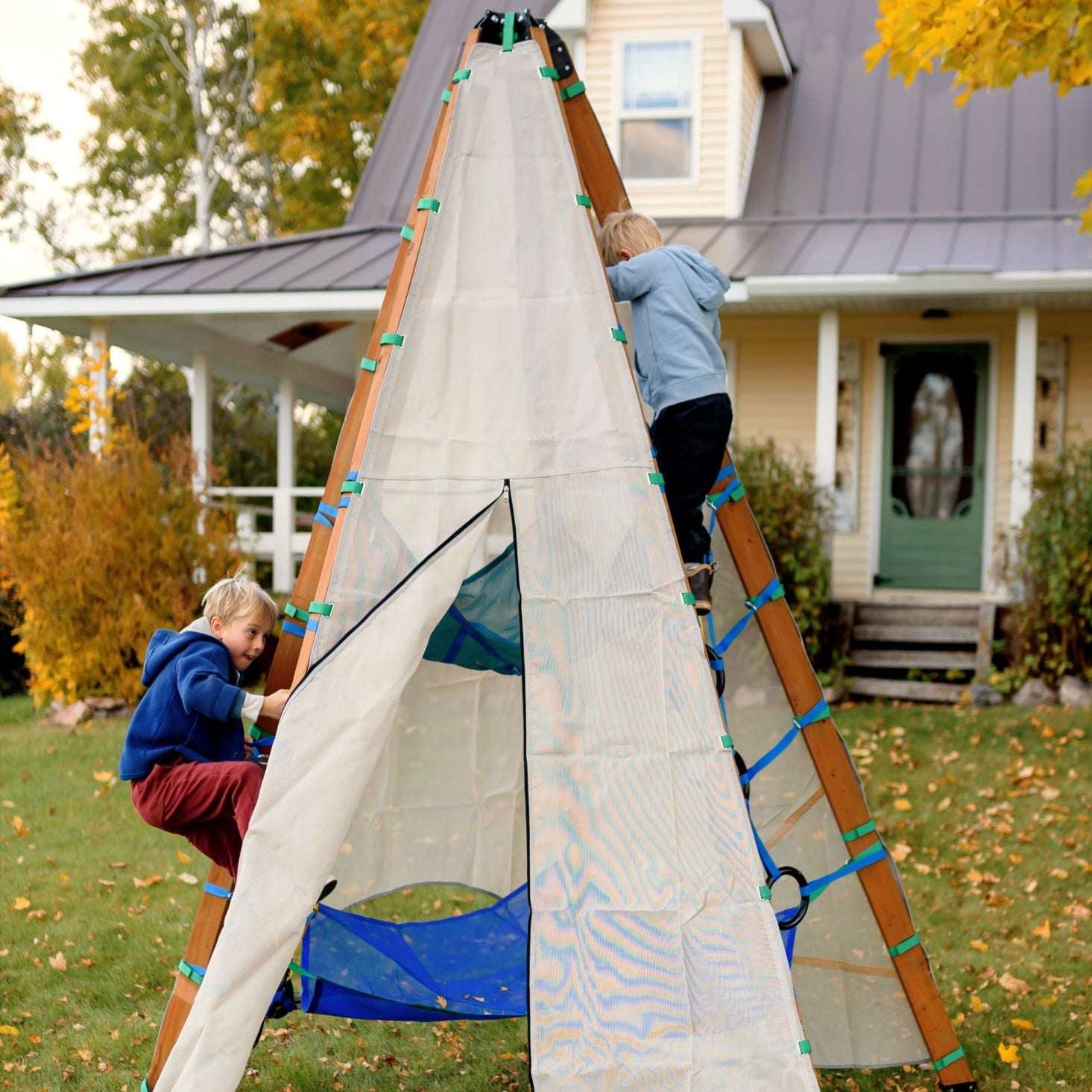 Children playing with a large white sail-like structure in a yard with a house in the background.