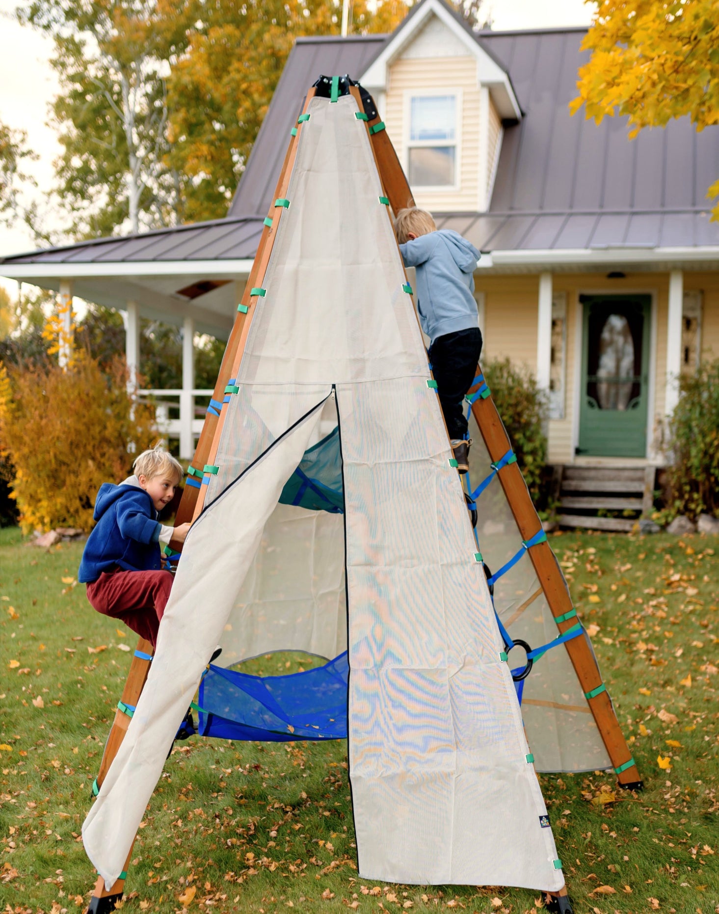 Children playing with a large white sail-like structure in a yard with a house in the background.
