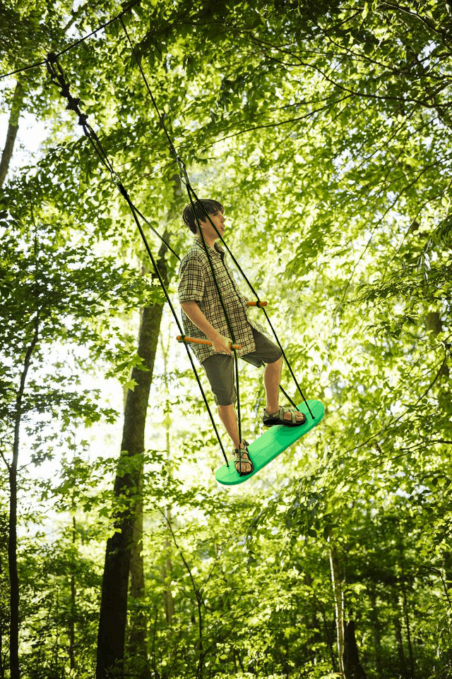 Person on a green swing set in a forest