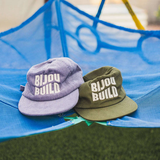 Two hats with 'Bijou Build' logo on a blue hammock