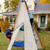 Children playing with a large white sail-like structure in a yard with a house in the background.
