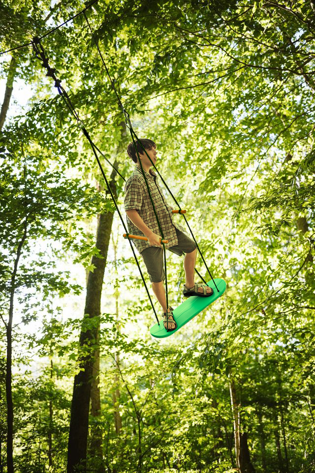 Person on a green swing set in a forest