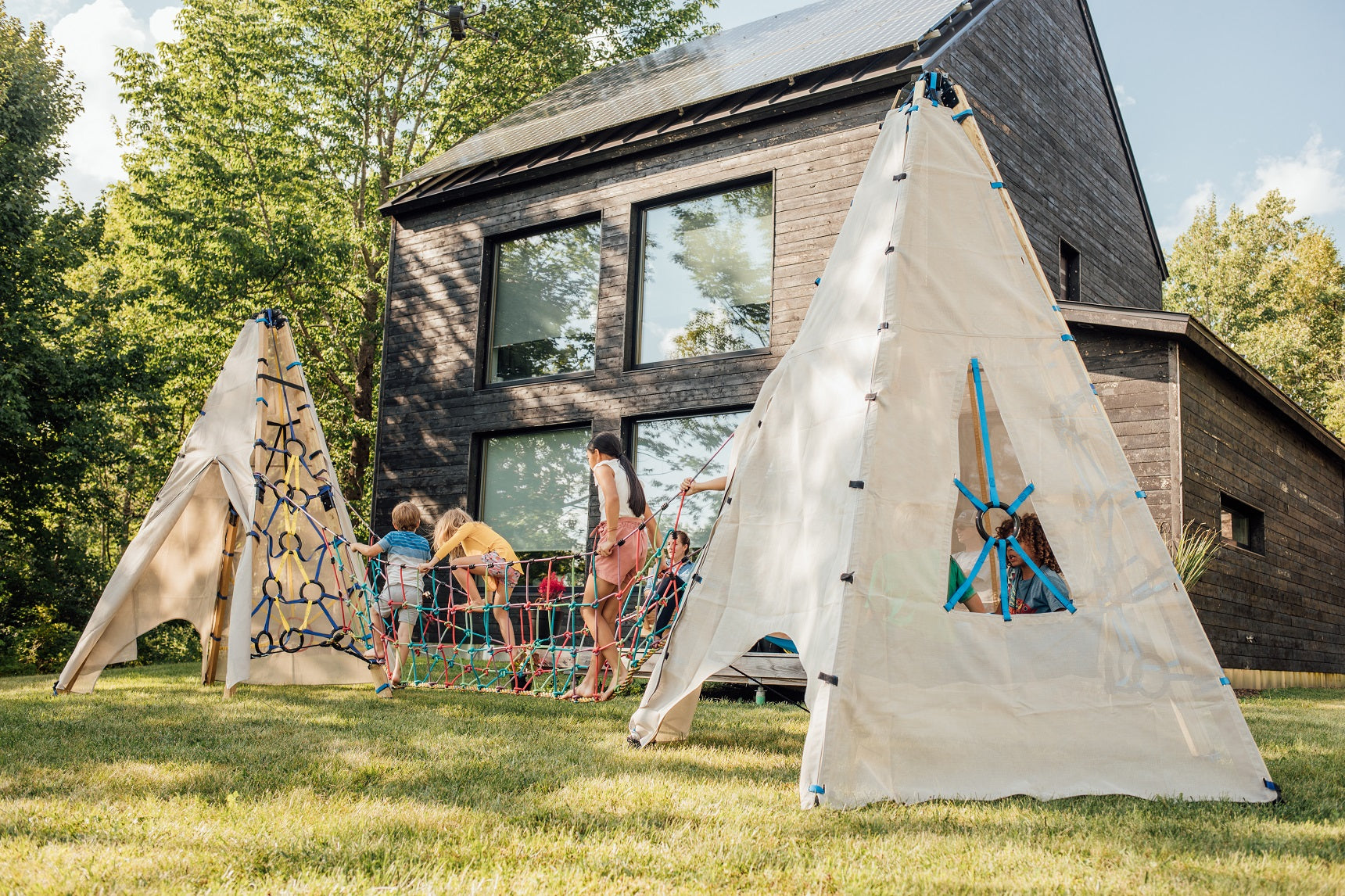 Children playing on a wooden climbing structure near a modern house.